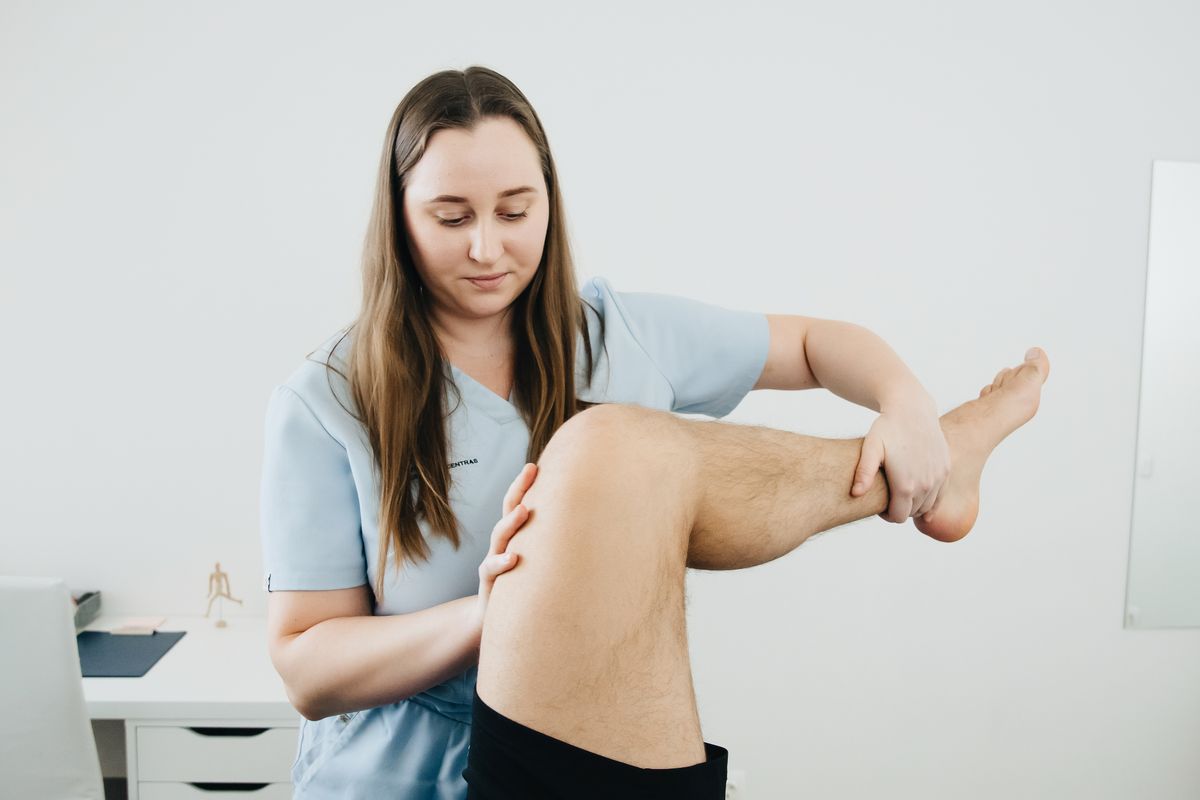 Physiotherapist supporting a bent knee and lower leg.